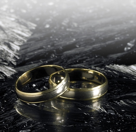 studio photography of two golden wedding rings on each other in icy ambianceの写真素材