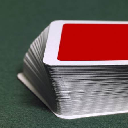 low angle studio photography showing a stack of red playing cards on green felt backgroundの写真素材