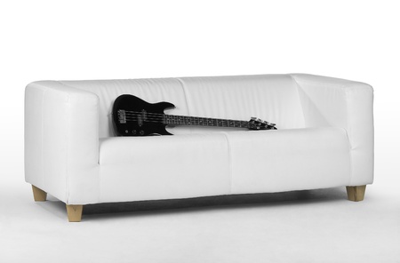 black bass guitar on white couch in light backの写真素材