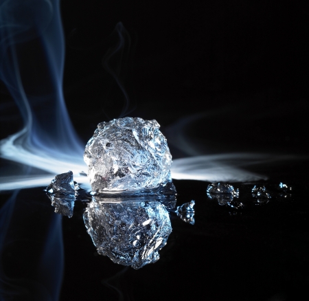 studio photography of a ice crystal and smoke in black reflective backの写真素材