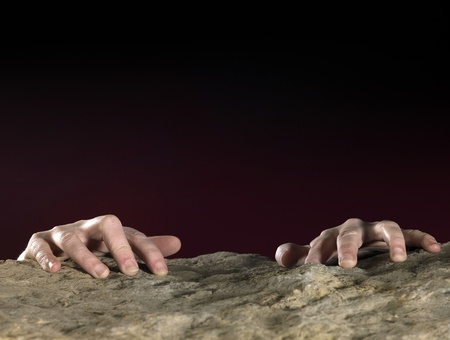 hands clutching on stone surface in dark backの写真素材