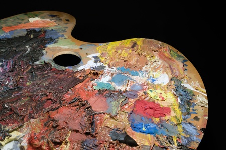 studio photography of a used old palette covered with paint in black backの写真素材