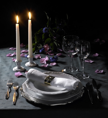 feastful place setting with floral deco and candlelight in dark backの写真素材