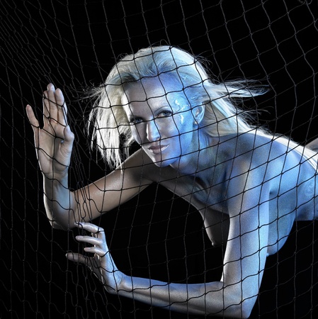 mystic mermaid theme showing a blue  bodypainted woman posing with net in black backの写真素材