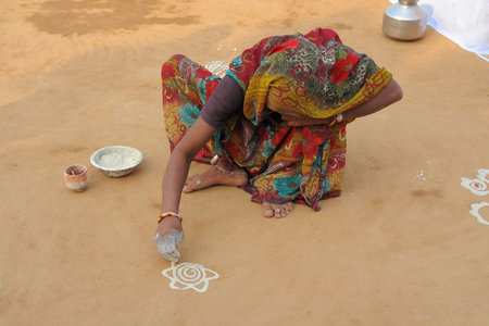 veiled woman sitting on the ground while painting an ornament in Karauli, Indiaのeditorial素材