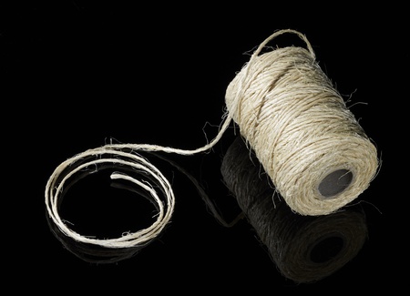 partly unrolled coil of yarn in dark backの写真素材