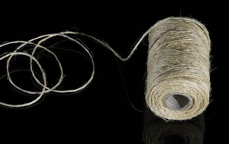 partly unrolled coil of yarn in dark backの写真素材