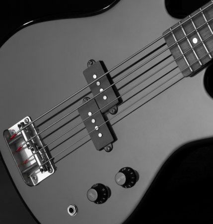 detail of a black bass guitar in dark backの写真素材