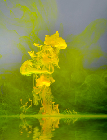 abstract floating yellow color on reflective water surface in grey backの写真素材