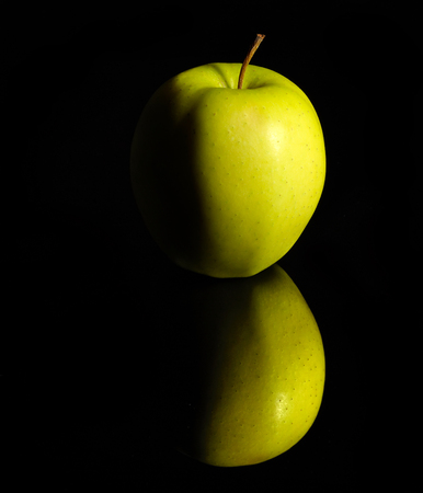 green apple on dark reflective groundの写真素材