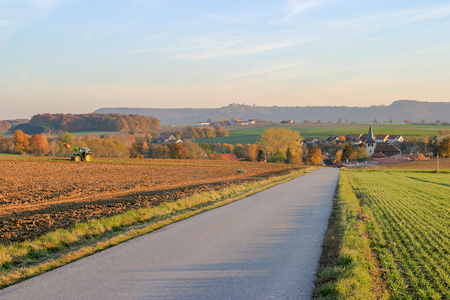 rural autumn scenery including a small road in Hohenlohe, a area in Southern Germany at evening timeの写真素材