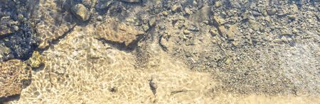 sunny illuminated detail of a small stream seen from above