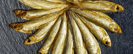 arrangement with lots of fresh smoked sprats on dark stone slab