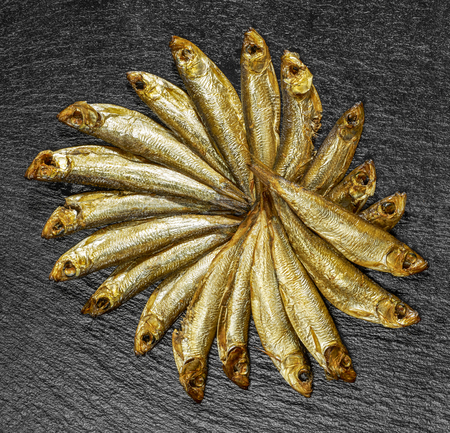 arrangement with lots of fresh smoked sprats on dark stone slabの写真素材