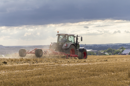 tractor on a stubble field in stormy ambianceの写真素材