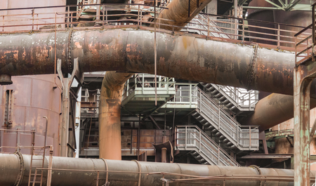 weathered rundown industrial scenery with old corroded steel girders, stairs and metal tubes