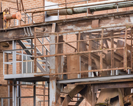 weathered rundown industrial scenery with old corroded steel girders, stairs and metal tubesの写真素材