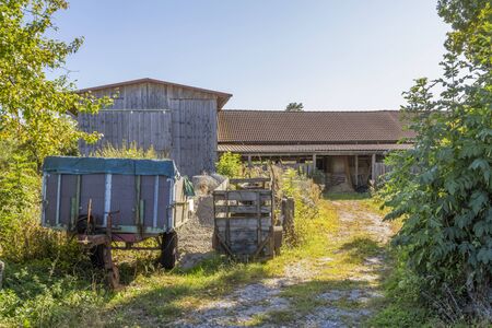 sunny agricultural scenery with trailer and barnsの写真素材