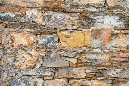 Full frame frontal detail of a vivid stone wall made of various stone types