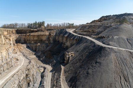 Scenery around an open-pit mine with gravel road, gravel and spoil piles in sunny ambianceの写真素材