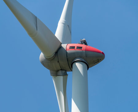 Low angle closeup shot of a sunny illuminated wind turbine nacelle in front of blue skyの写真素材