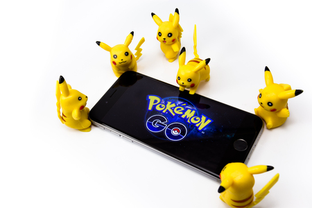 Apple iPhone 6s and Pokemon Go on the screen, a free-to-play augmented reality mobile game developed by Niantic for iOS and Android devices, with Pickachu toys character from Pokemon anime. Omsk, Russia - August 20, 2016のeditorial素材