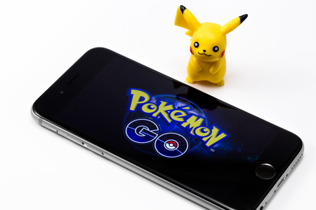 Apple iPhone 6s and Pokemon Go on the screen, a free-to-play augmented reality mobile game developed by Niantic for iOS and Android devices, and Pickachu toy character from Pokemon anime. Omsk, Russia - August 20, 2016のeditorial素材