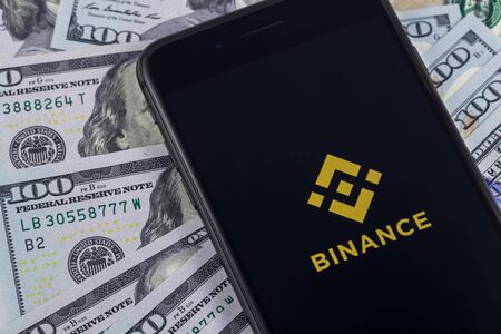 Apple iPhone and Binance logo, and dollars. Binance is a cryptocurrency exchange. Ekaterinburg,...