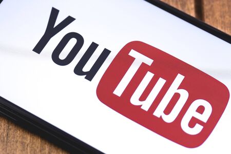 smartphone with YouTube logo on the wooden background. Moscow, Russia - October 26, 2018