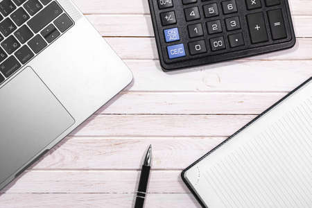 Beige wooden desk table with pen, notepad, calculator and Macbook. Apple Inc. is an American multinational technology company. Moscow, Russia - April 26, 2019のeditorial素材