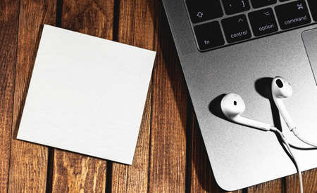 closeup macro wooden table with Macbook and Earpods, clear note. Apple Inc. is an American...