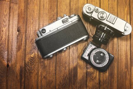 two retro cameras and light meter on wooden boards background