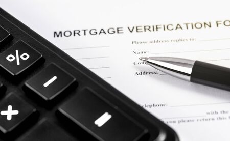 mortgage verification form application with black pen and calculator closeup