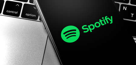 closeup Macbook and iPhone with Spotify logo on the screen. Spotify - online streaming audio service. Moscow, Russia - July 05, 2019のeditorial素材
