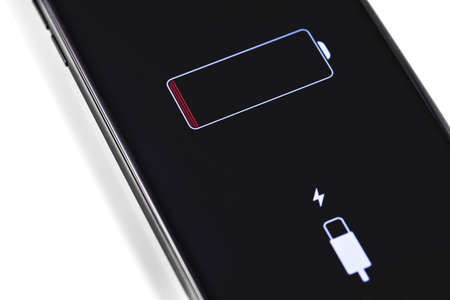 Apple iPhone smartphone with battery logo on the screen. Apple is a multinational technology company that designs, develops, sells electronics, computer software, online services. Moscow, Russia - July 12, 2019のeditorial素材
