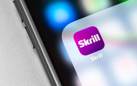 Skrill app on the screen smartphone, notebook closeup. Skrill - electronic payment system. Moscow, Russia - December 19, 2019のeditorial素材