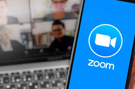 Zoom logo on the screen smartphone with notebook blurred background closeup. Zoom Video Communications is a company that provides remote conferencing services. Moscow, Russia - April 1, 2020のeditorial素材