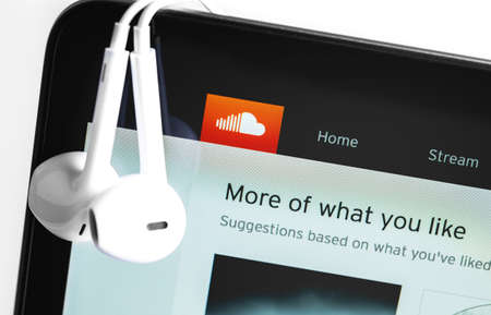 Soundcloud website on the screen notebook with Apple Earpods. SoundCloud is a global online audio...