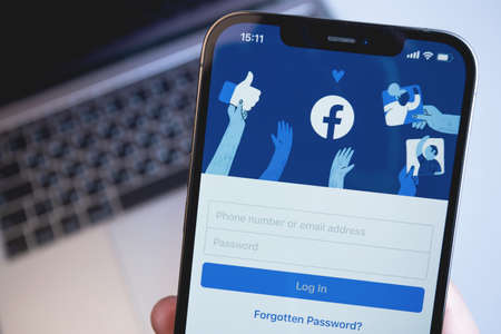 Facebook mobile app on the screen iPhone, notebook closeup. Facebook is largest and most popular social networking site in the world. Moscow, Russia - December 5, 2020のeditorial素材