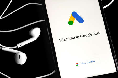 Google Ads (AdWords) logo on the screen smartphoneand and Earpods on black background. Google Ads is a service of contextual, basically, search advertising from Google. Moscow, Russia - June 10, 2020のeditorial素材