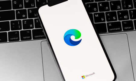 Microsoft Edge mobile app browser on the screen smartphone with laptop closeup. Microsoft Edge is a browser from Microsoft. Moscow, Russia - December 3, 2020