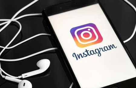 Instagram on the screen smartphone and Apple Earpods on black background. Instagram is a...