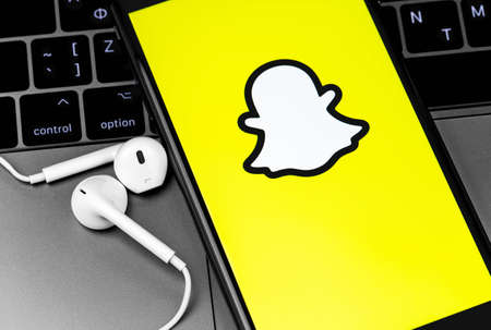 Snapchat logo on the screen iPhone with Earpods headphones. Snapchat is a mobile messaging app with attached photos and videos. Moscow, Russia - July 22, 2020のeditorial素材