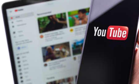 YouTube logo on the screen smartphone and YouTube homepage on the display laptop. YouTube is a free video sharing application that anyone can watch. Moscow, Russia - April 20, 2020のeditorial素材