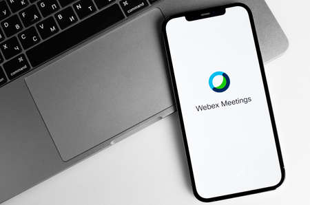 Webex Meetings logo mobile app on screen smartphone iPhone and Macbook notebook. Webex Meetings is one of popular application offering cloud meeting or video conference. Moscow, Russia - January 12, 2021のeditorial素材