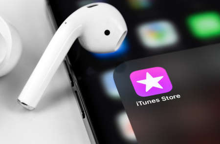 iTunes icon app on the screen iPhone with AirPods closeup, macro. Apple is a multinational technology company that designs, develops, online services. Moscow, Russia - June 12, 2021のeditorial素材