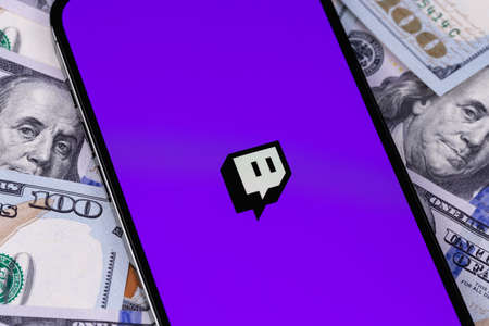 Twitch logo on screen smartphone iPhone with dollars, money closeup. Twitch is a video streaming service specializing in computer games. Moscow, Russia - September 27, 2021のeditorial素材