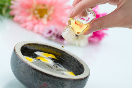 Essential oil dripping into petal water, with hand holding the glass bottle, blur backgroundの写真素材