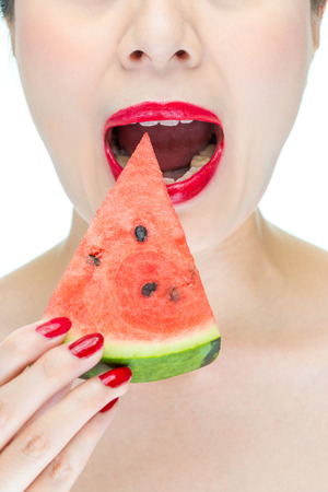 Fashion woman enjoy eating watermelon with red lips, red nail polishの写真素材