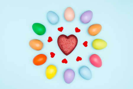 Colorful easter eggs around the heart shape on pastel backgroundの写真素材